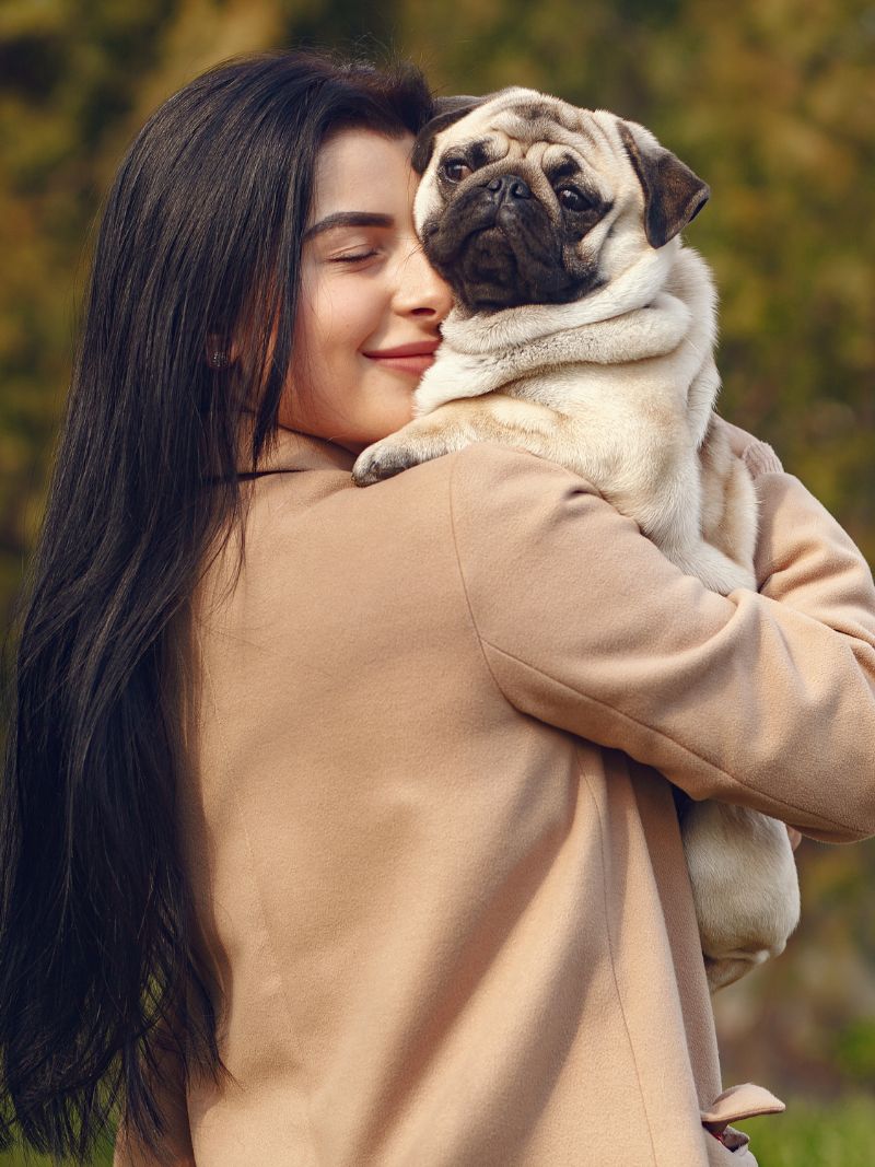 A woman cradles a pug dog in her arms